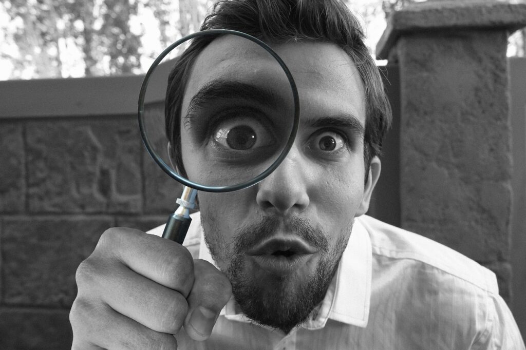 writing research; man looking through a magnifying glass