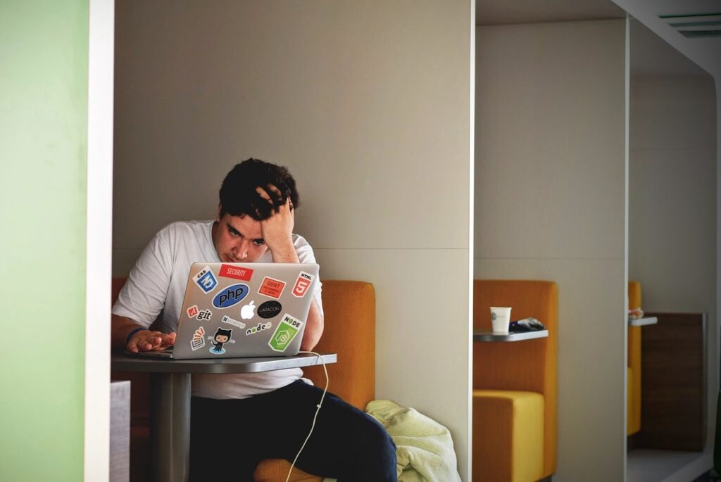 frustrated man trying to write on a laptop unsuccessfully, writer's block concept